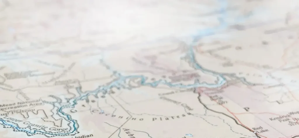 Faded, top-down view of a topographical map showing a river and plateau regions.